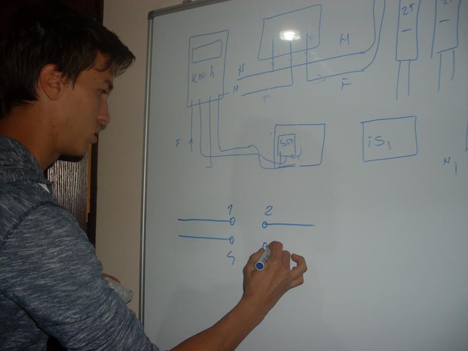 Alex deseneaza pe tabla de la practica modul de conexiune la un intrerupator cruce.jpg